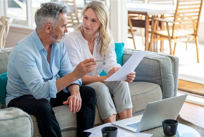 man and woman on sofa talking over paperwork